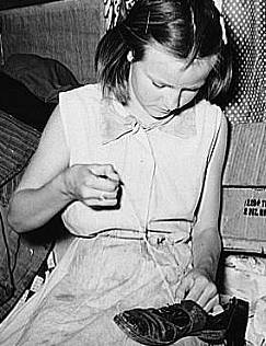 Great Depression: Daughter of white migrants repairing shoes with cotton thread. Sebastian, Texas. Photo by Russell Lee. Courtesy Library of Congress, Prints & Photographs Division, FSA-OWI Collection LC-USF34- 032323-D